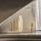 Preview: Maßgefertigte Edelstahl-Kleiderstange an einer schrägen Decke montiert, mit Kleidung, die daran hängt