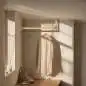 Preview: Maßgefertigte Edelstahl-L-förmige Garderobenstange Holzstab, montiert in einem stilvollen Raum mit Kleidung, die an der Stange hängt.